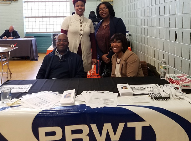 PRWT staff posing for a photo in front of a table with their logo and educational materials.