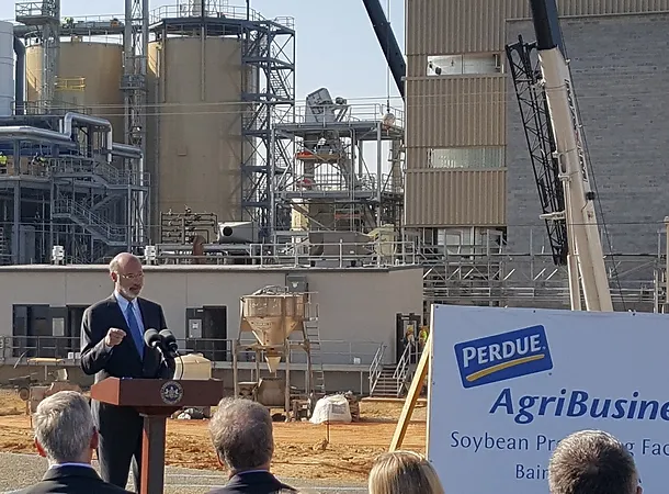 Governor Tom Wolf stands in front of a Perdue building construction site giving a speech.