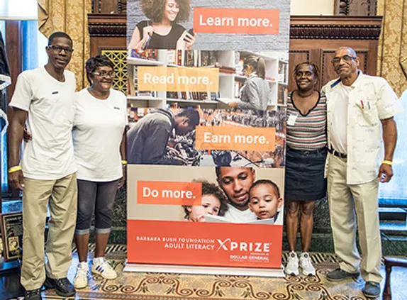 Four advocates stand by an XPRIZE banner supporting education.