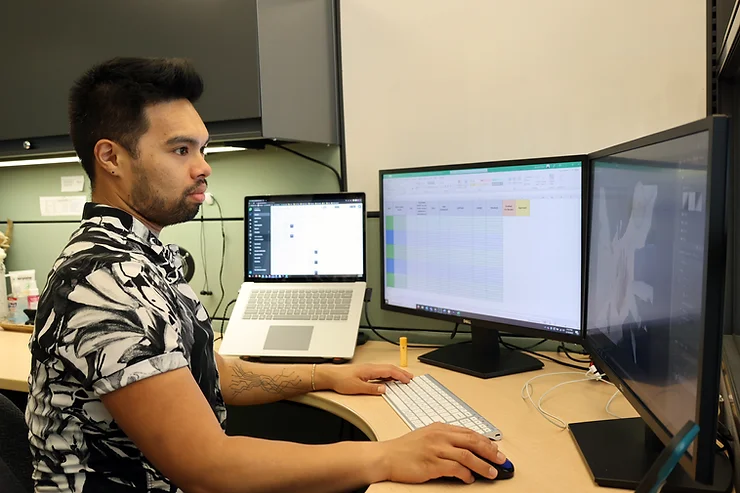 Kenneth Hilario sits at his desk looking at a computer screen