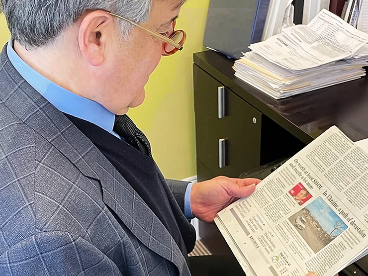 Larry Ceisler reading a newspaper at a desk