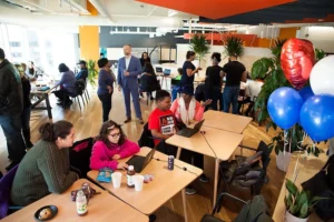 A cheerful event for Coded By Kids, a Ceisler Media client. Kids sit at computers with parents while other adults stand around the room socializing.