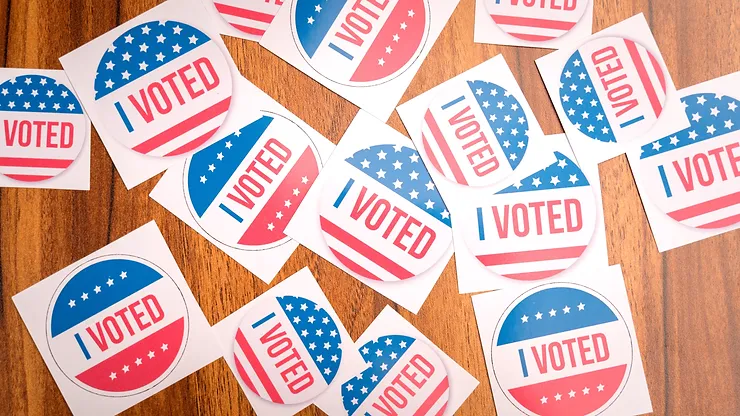 I Voted stickers with American flag designs sitting on a wooden table