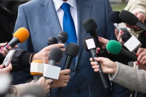 Microphones surrounding a man in a suit with a blue tie