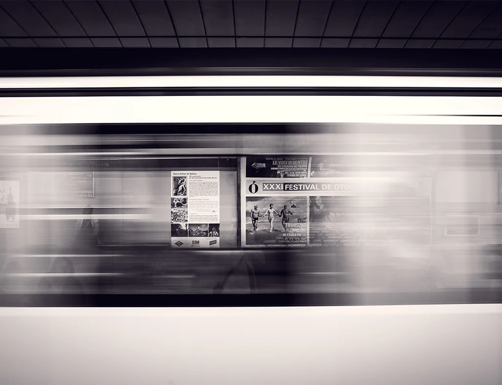 A black and white moving train with advertisements