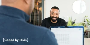 Two men speaking over a laptop in a clean, professional office setting