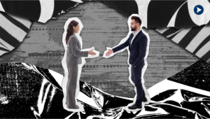 A woman and man in business suits reach out to shake each other's hands.